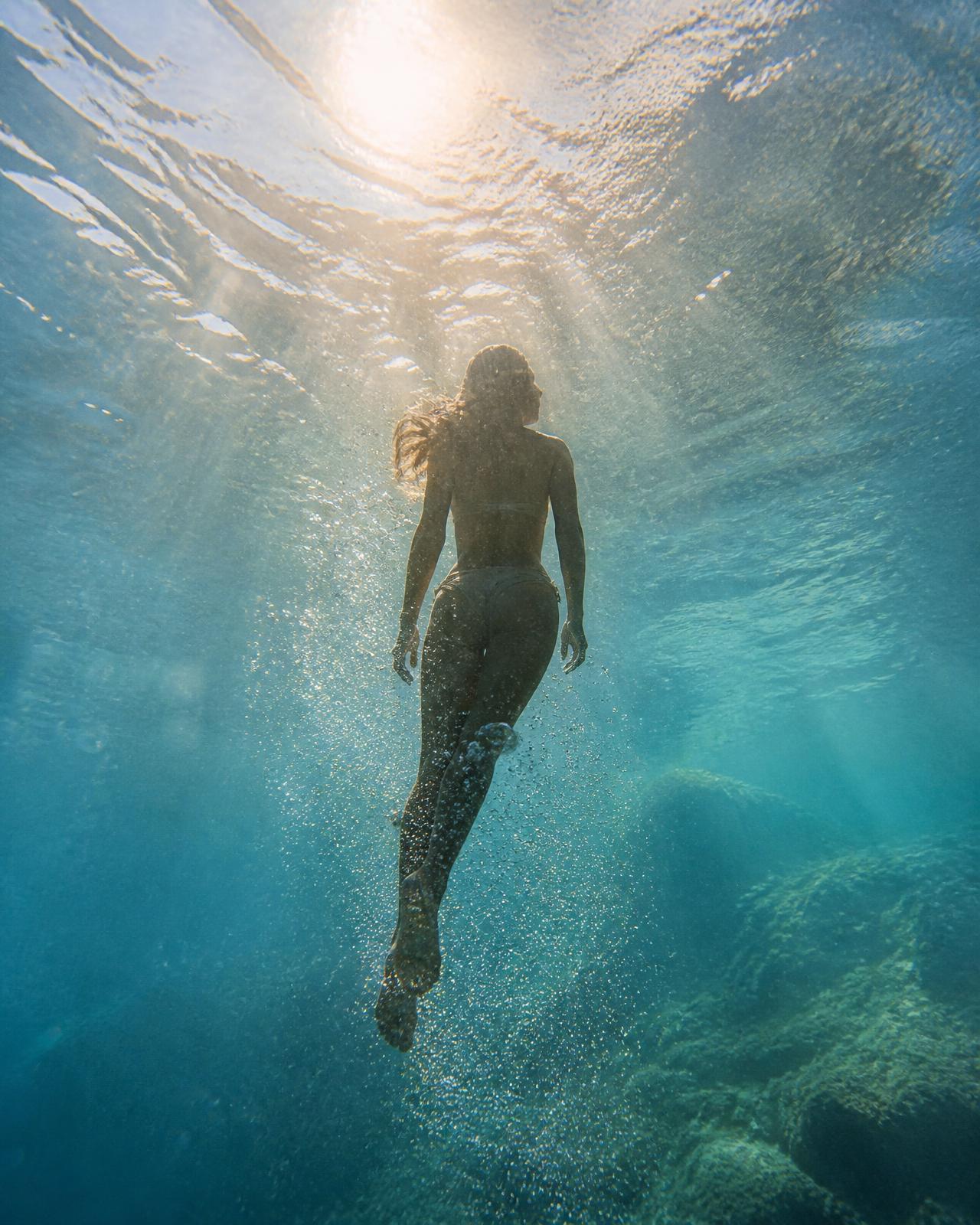 A swimmer rising toward sunlight in clear Mediterranean water